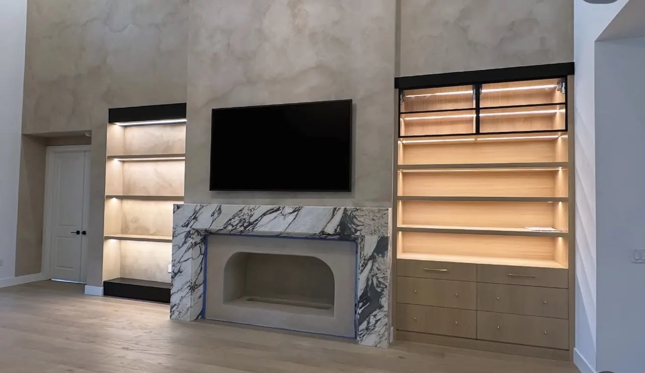 Finished feature wall with lit shelving and stone fireplace